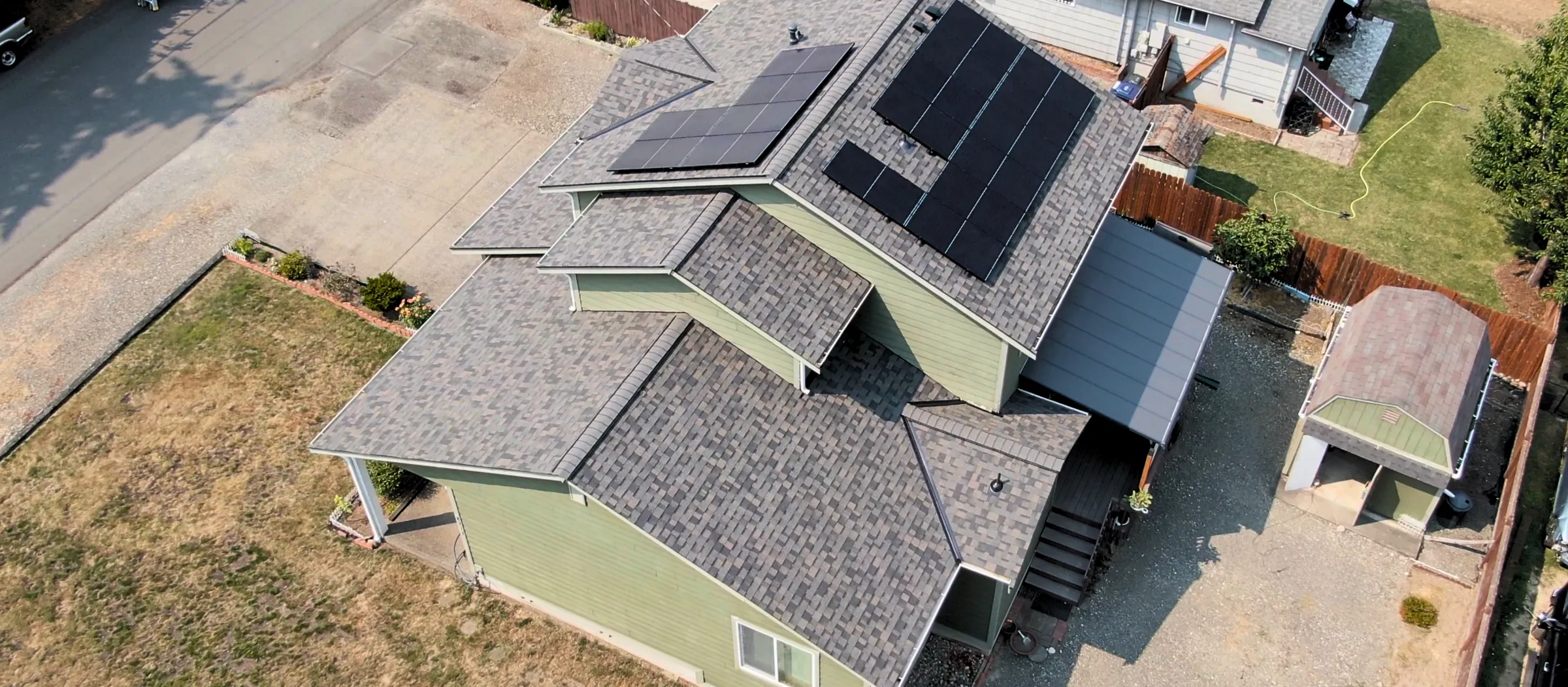 Aerial view of a home with solar panels mounted on its asphalt-shingle roof
